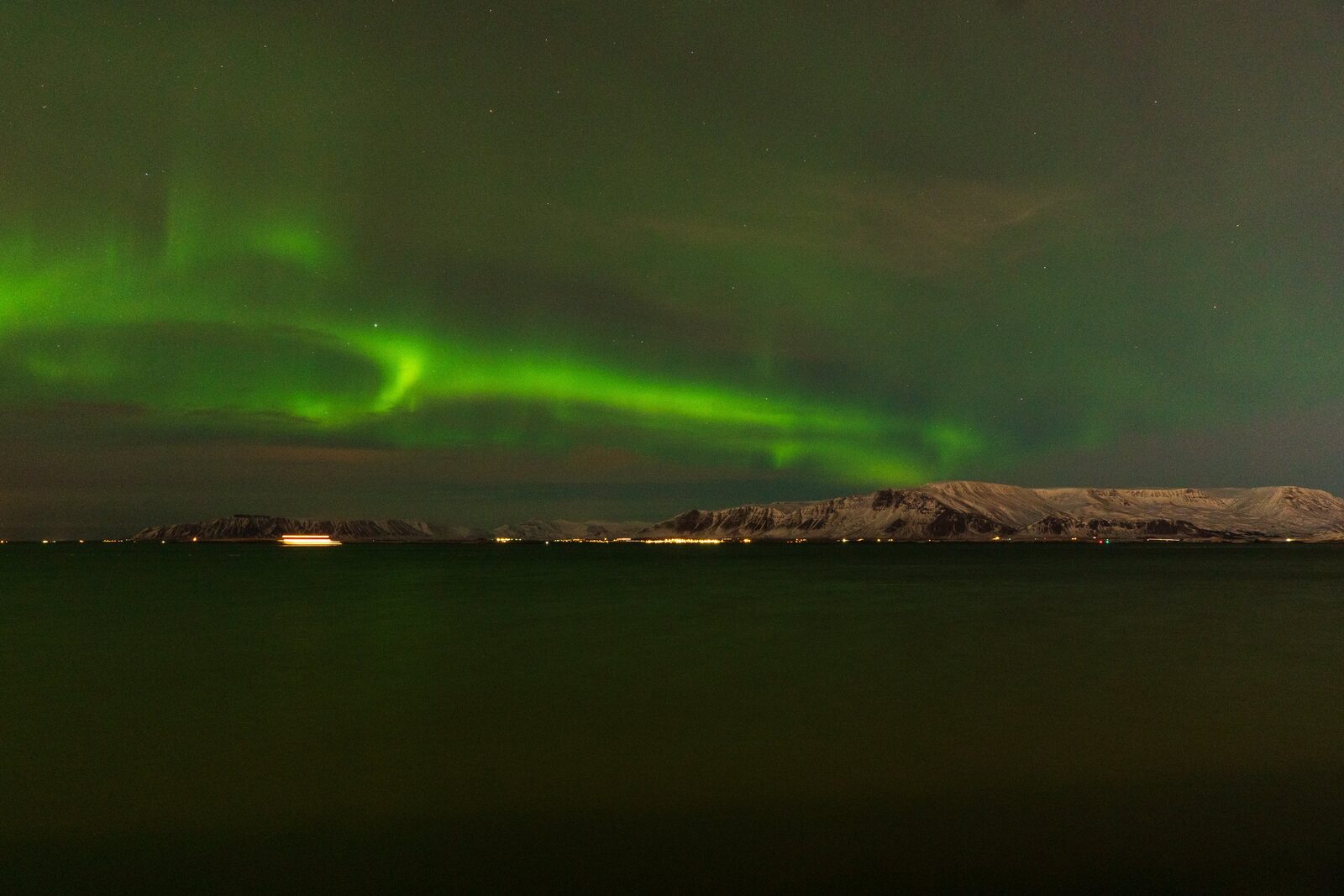 Northern lights circular swirl pattern over Iceland bay
