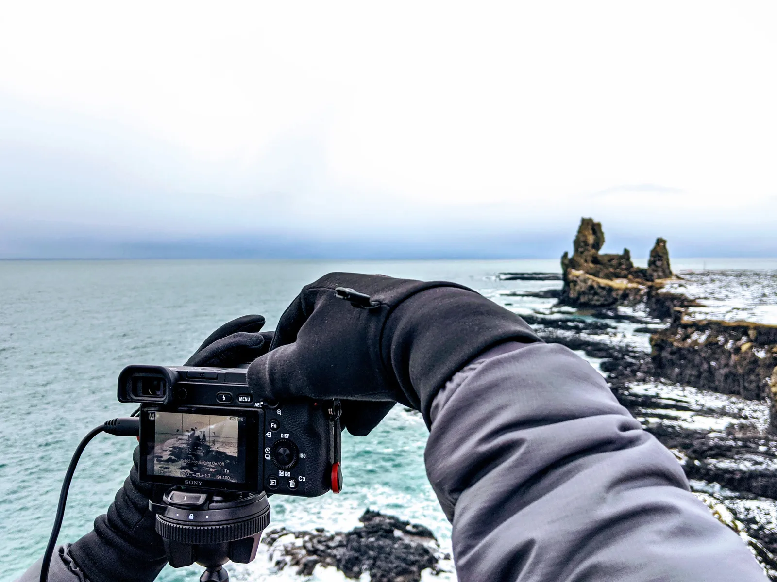 A photographer composing the sea stacks through a camera